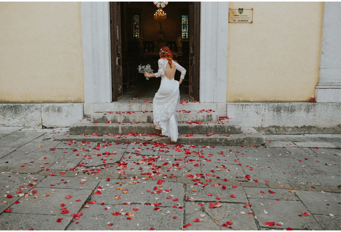 bride in front of church floor covered with roses